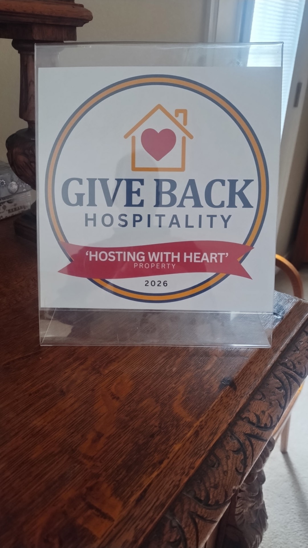 Hosting With Heart property badge displayed on a side table